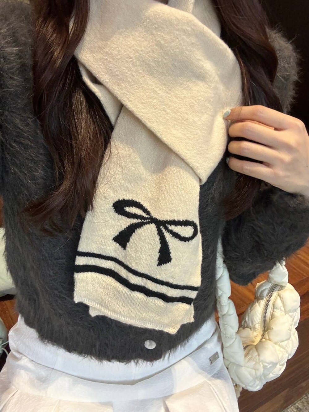 ホワイト系のショルダーバッグ、グレー系のカーディガン/ボレロ、ホワイト系のスカートを着用したレディースの秋コーディネートの3枚目の写真