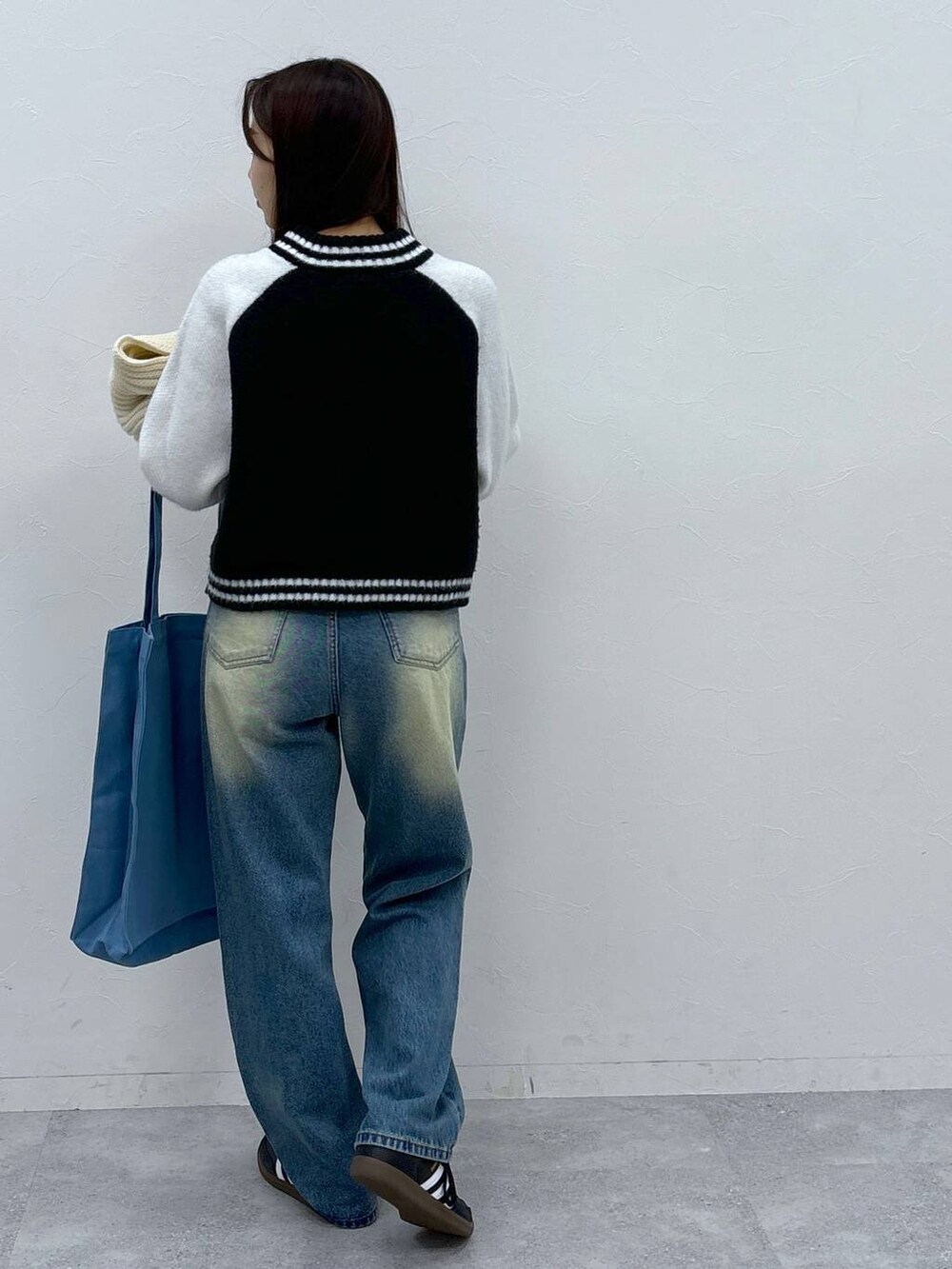 ブルー系のトートバッグ、ブルー系のデニムパンツ、ホワイト系のニット/セーターを着用したレディースの秋コーディネートの5枚目の写真