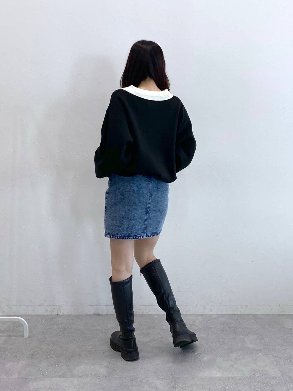 ブラック系のニット/セーター、ブルー系のデニムスカートを着用したレディースの冬コーディネートの5枚目の写真