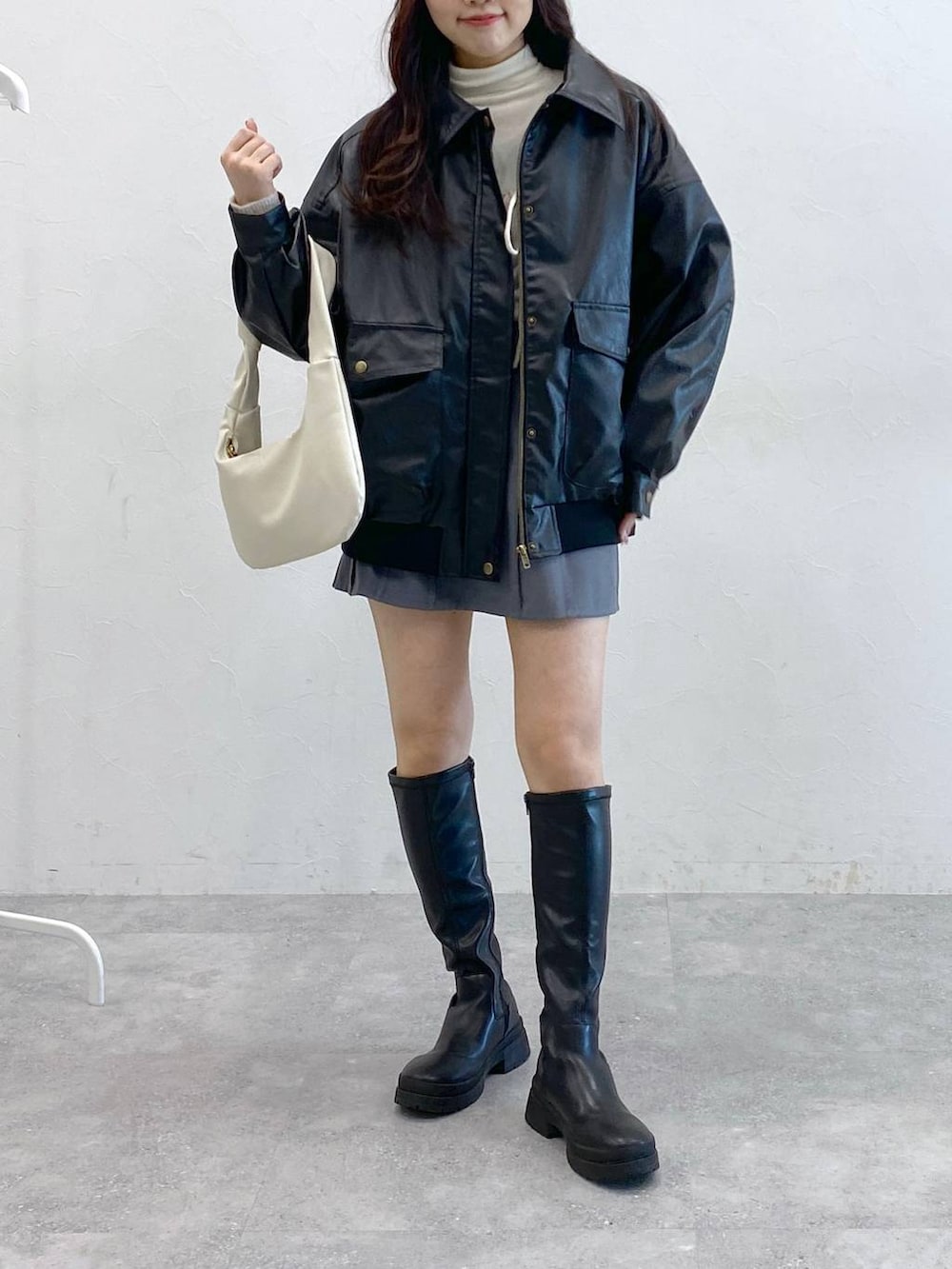 グレー系のスカート、ブラック系のブルゾン、ベージュ系のTシャツ/カットソーを着用したレディースの冬コーディネートの2枚目の写真