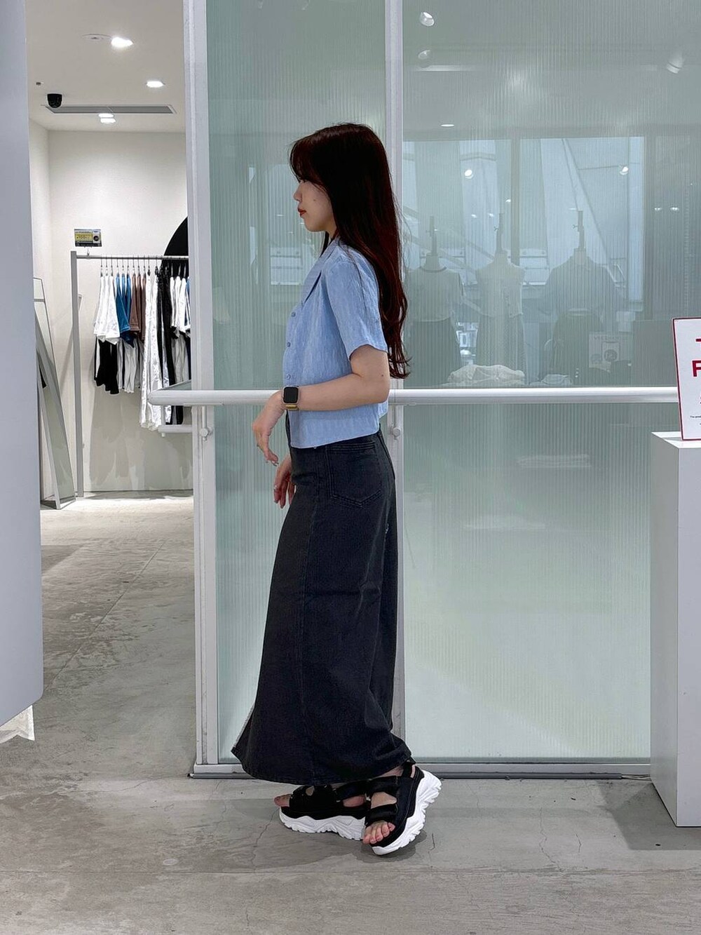 ブラック系のスカート、ブラック系のサンダル、ベージュ系のTシャツ/カットソーを着用したレディースの夏コーディネートの2枚目の写真