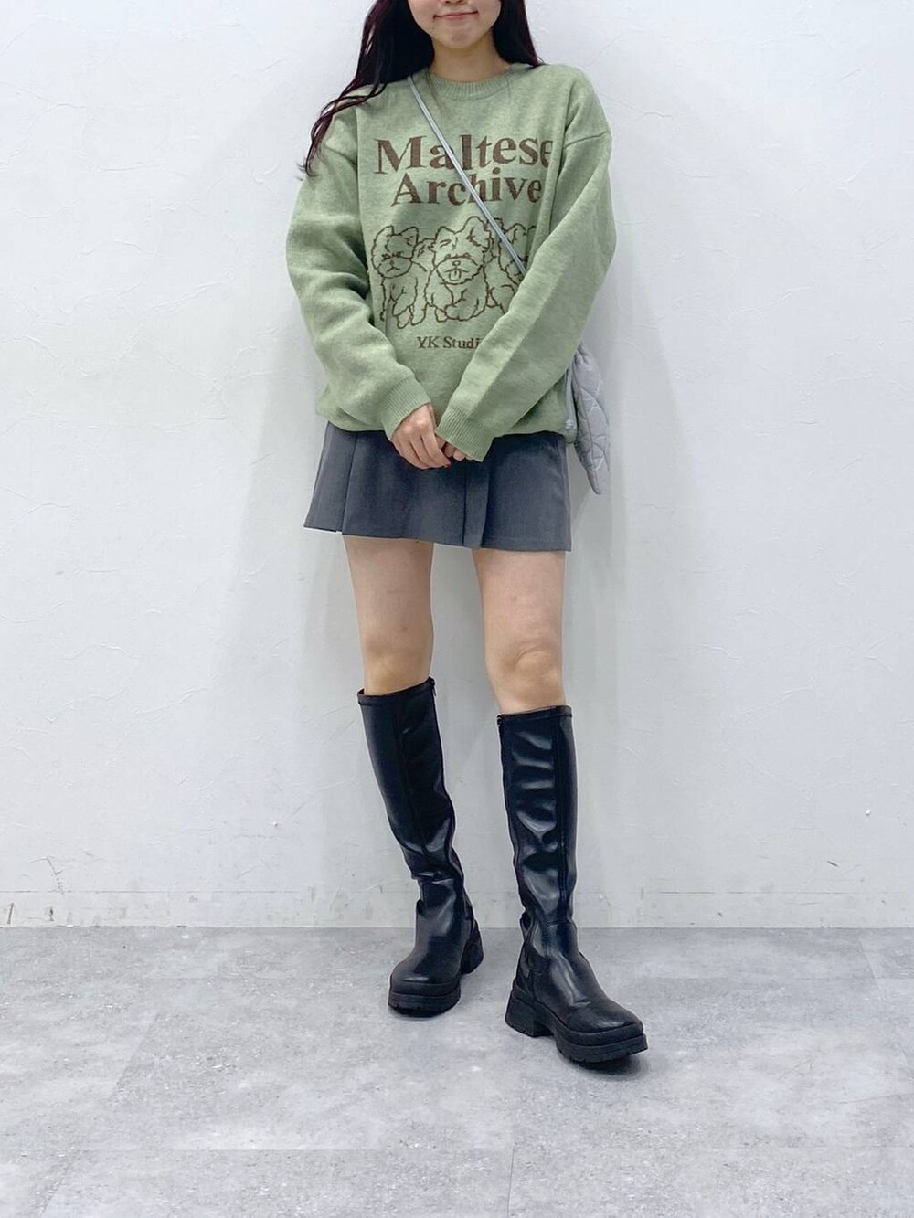 グリーン系のニット/セーター、グレー系のショルダーバッグ、グレー系のスカートを着用したレディースの冬コーディネートの2枚目の写真