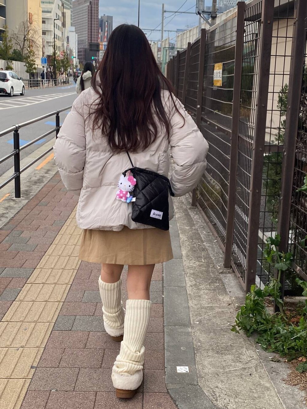 ブラック系のショルダーバッグ、ブラウン系のスカートを着用したレディースの冬コーディネートの3枚目の写真