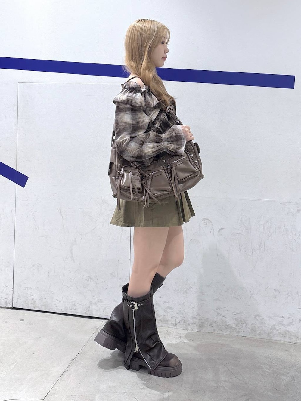 ブラウン系のショルダーバッグ、ベージュ系のスカート、ブラウン系のブーツを着用したレディースの秋コーディネートの4枚目の写真