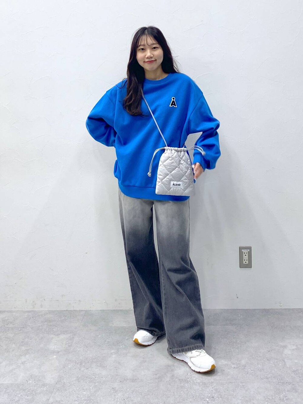 グレー系のショルダーバッグ、ブラック系のデニムパンツ、ブルー系のスウェットを着用したレディースの冬コーディネートの2枚目の写真