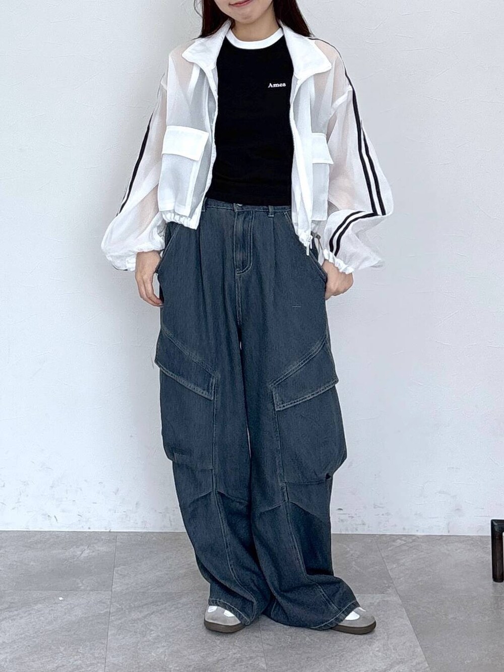 ブルー系のカーゴパンツ、ブラック系のタンクトップ、ホワイト系のブルゾンを着用したレディースの春コーディネートの4枚目の写真