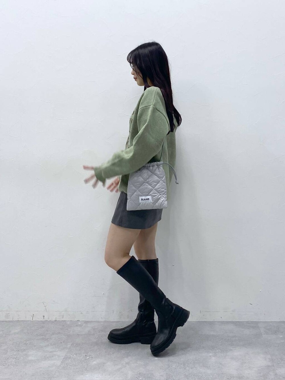 グリーン系のニット/セーター、グレー系のショルダーバッグ、グレー系のスカートを着用したレディースの冬コーディネートの3枚目の写真