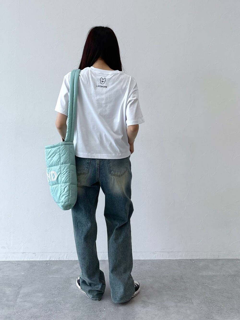 ブルー系のデニムパンツ、グリーン系のショルダーバッグ、ホワイト系のTシャツ/カットソーを着用したレディースの夏コーディネートの6枚目の写真