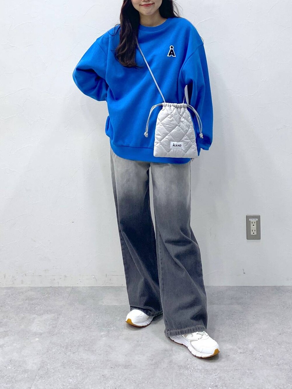 グレー系のショルダーバッグ、ブラック系のデニムパンツ、ブルー系のスウェットを着用したレディースの冬コーディネートの3枚目の写真