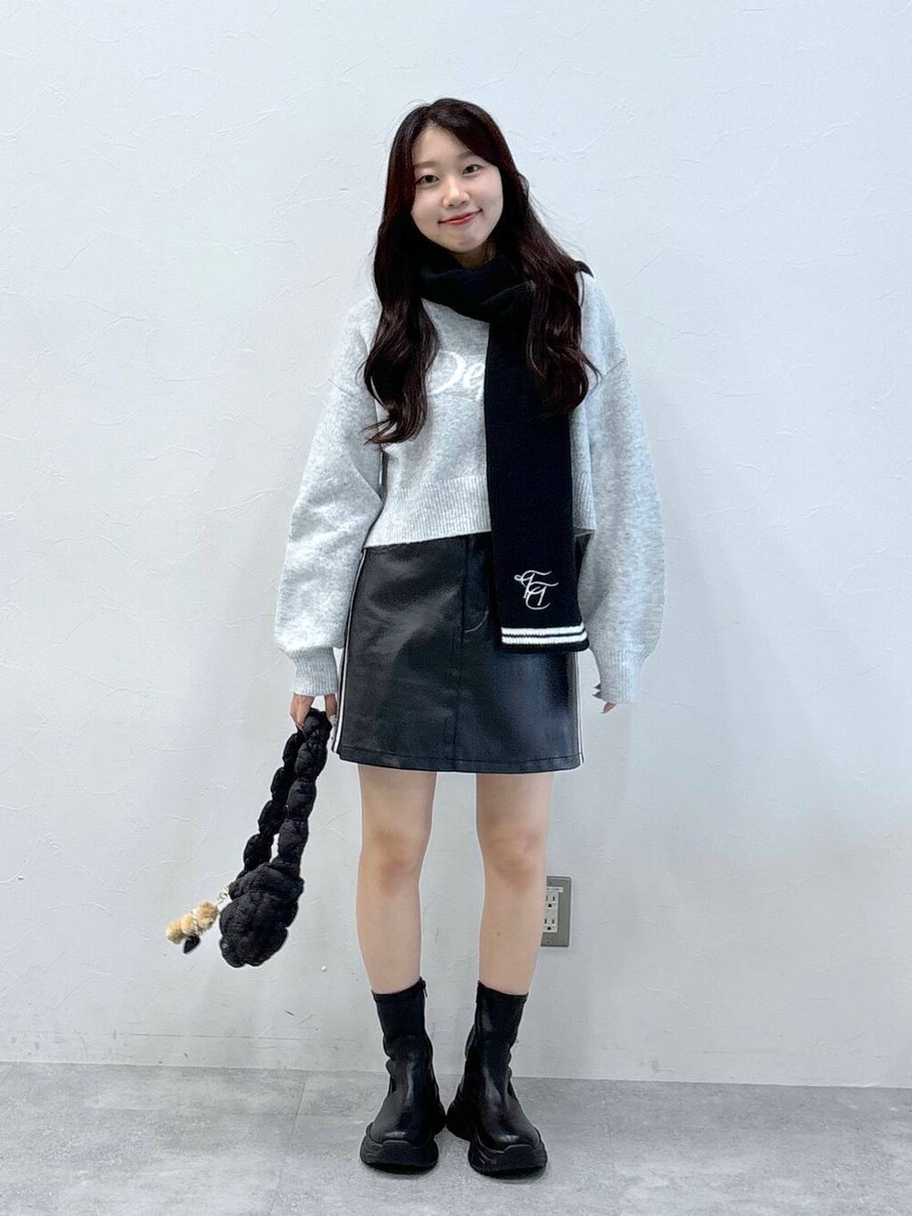 ブラック系のショルダーバッグ、グレー系のニット/セーター、ブラック系のスカートを着用したレディースの秋コーディネートの3枚目の写真