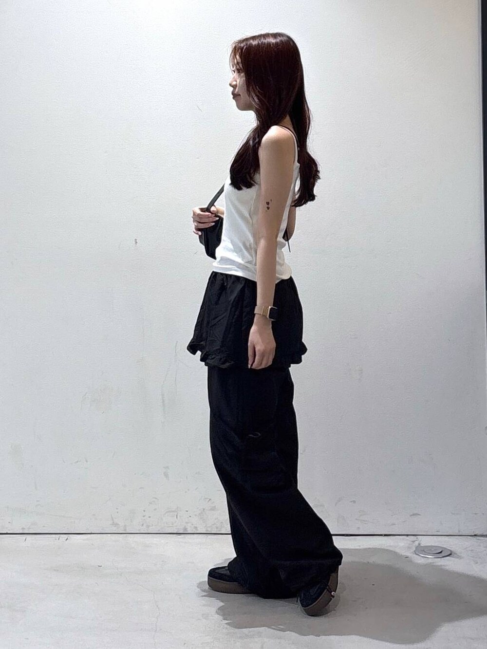 ブラック系のトートバッグ、ホワイト系のタンクトップ、ブラック系のカーゴパンツを着用したレディースの夏コーディネートの3枚目の写真