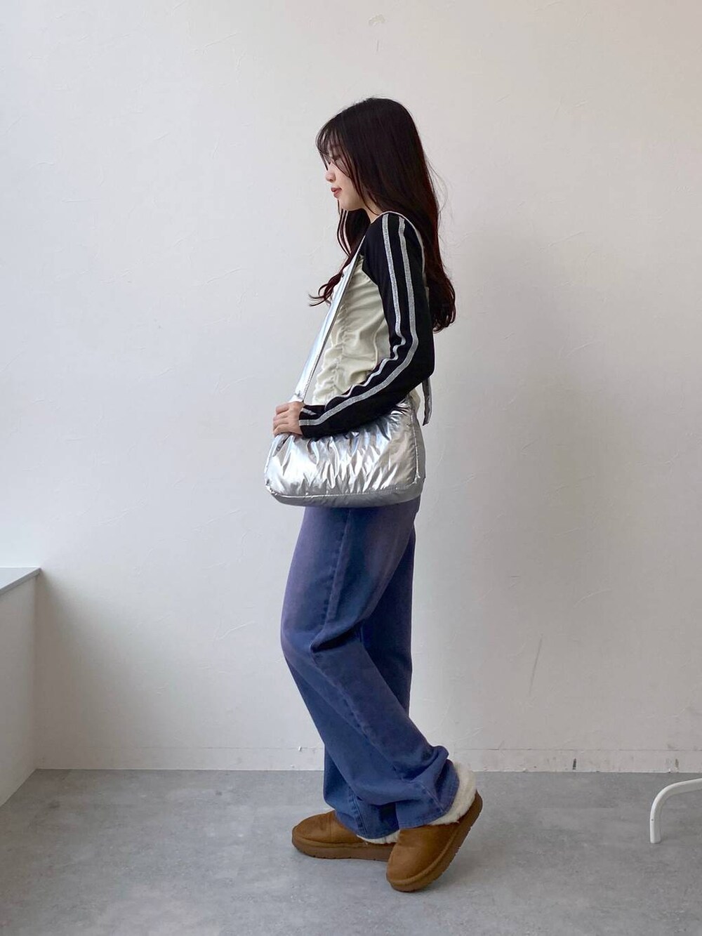 パープル系のデニムパンツ、その他のショルダーバッグ、ベージュ系のTシャツ/カットソーを着用したレディースの冬コーディネートの3枚目の写真