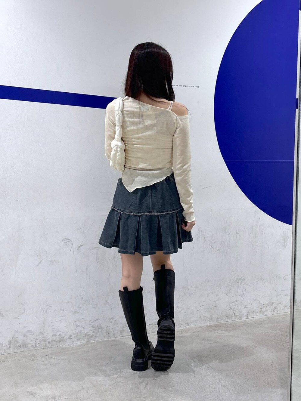 ホワイト系のショルダーバッグ、ベージュ系のTシャツ/カットソー、ブルー系のデニムスカートを着用したレディースの秋コーディネートの4枚目の写真