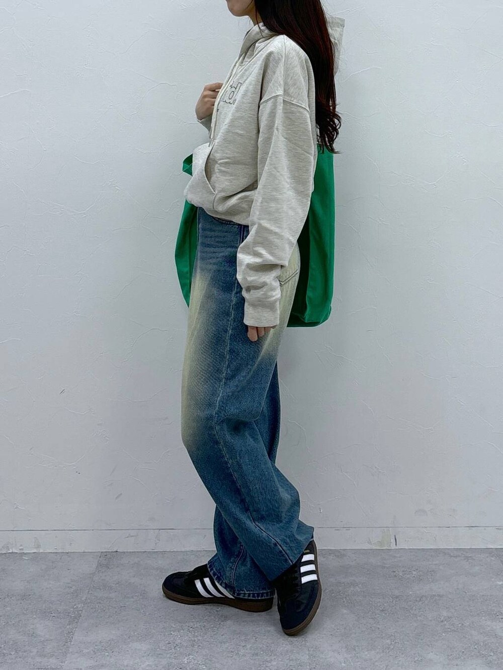 ブルー系のデニムパンツ、グリーン系のトートバッグを着用したレディースの秋コーディネートの3枚目の写真