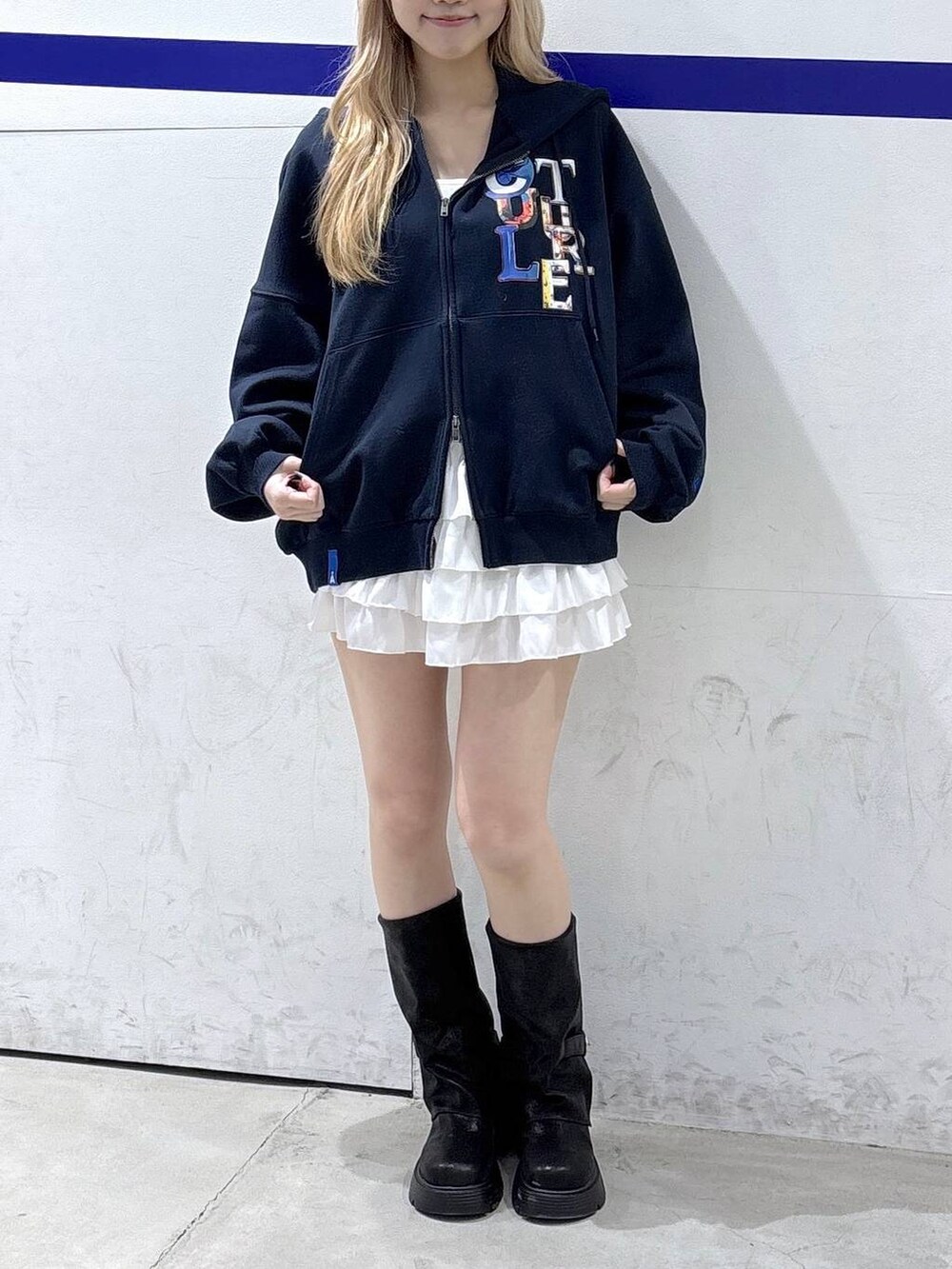 ブラック系のブーツ、ホワイト系のスカート、ブルー系のパーカーを着用したレディースの冬コーディネートの2枚目の写真