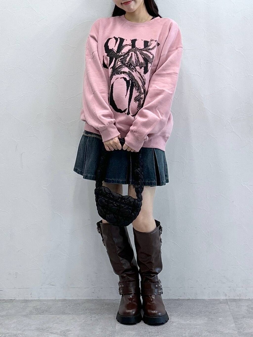 ブラック系のショルダーバッグ、ブルー系のデニムスカート、ブラウン系のブーツを着用したレディースの秋コーディネートの3枚目の写真