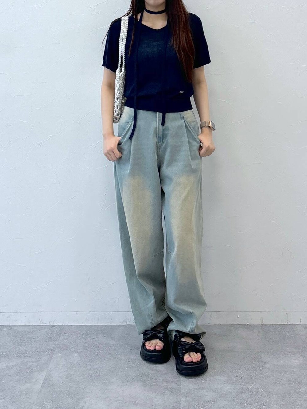 ブルー系のデニムパンツ、ブラック系のサンダル、ベージュ系のトートバッグを着用したレディースの夏コーディネートの2枚目の写真