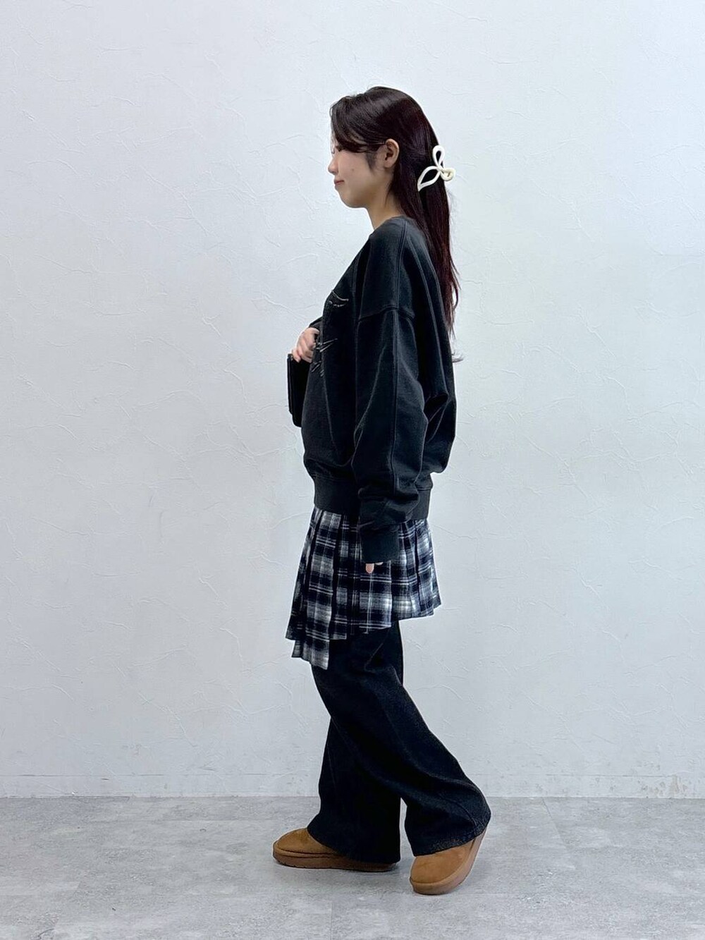 ブラック系のデニムパンツ、ブラック系のハンドバッグ、ブルー系のスカートを着用したレディースの冬コーディネートの4枚目の写真