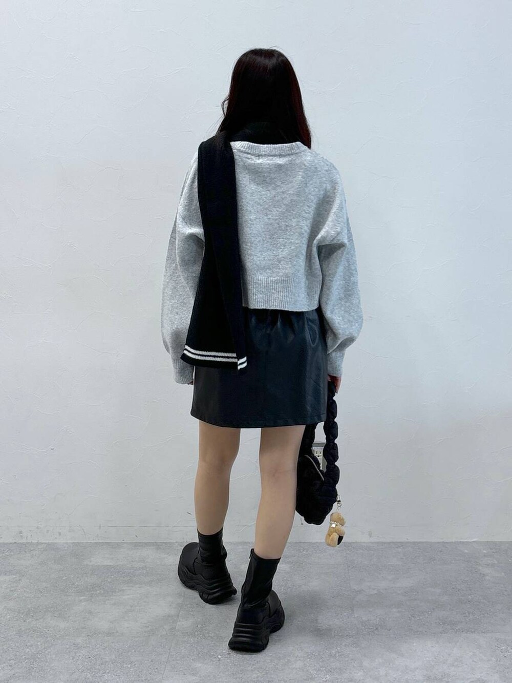 ブラック系のショルダーバッグ、グレー系のニット/セーター、ブラック系のスカートを着用したレディースの秋コーディネートの5枚目の写真