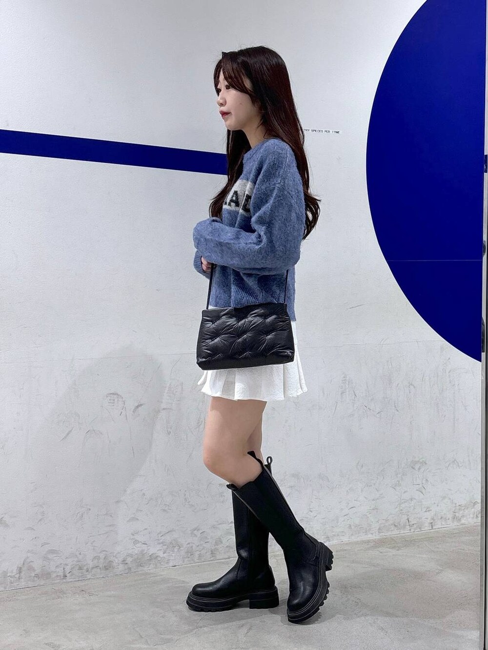 ホワイト系のスカート、ブラック系のブーツ、ブラック系のショルダーバッグを着用したレディースの秋コーディネートの3枚目の写真