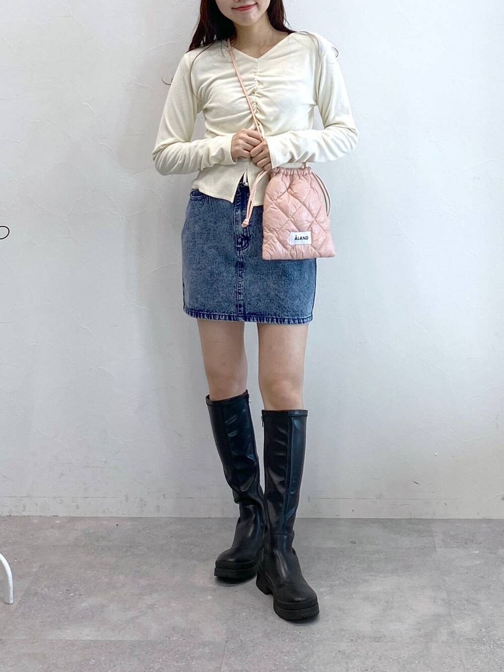 ブルー系のデニムスカート、ピンク系のショルダーバッグ、ベージュ系のTシャツ/カットソーを着用したレディースの冬コーディネートの2枚目の写真