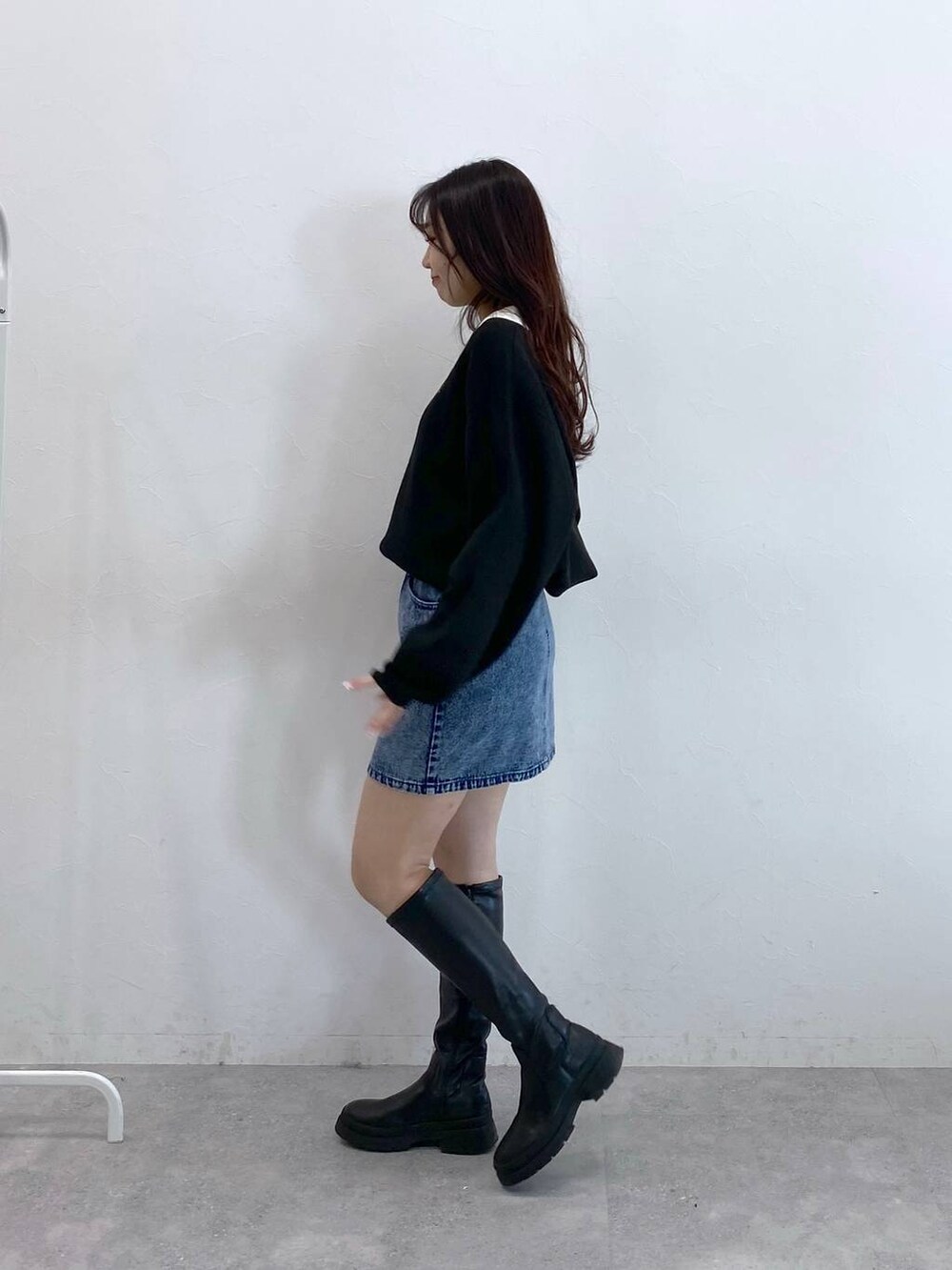 ブラック系のニット/セーター、ブルー系のデニムスカートを着用したレディースの冬コーディネートの4枚目の写真