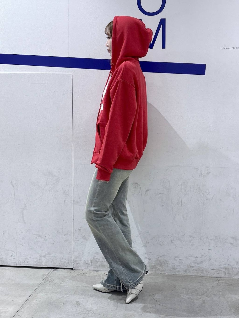 ブルー系のデニムパンツ、ホワイト系のパンプス、レッド系のパーカーを着用したレディースの春コーディネートの3枚目の写真