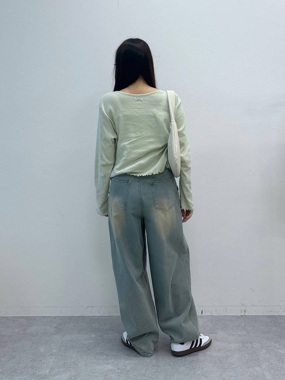 ブルー系のデニムパンツ、ベージュ系のチューブトップ、グリーン系のカーディガン/ボレロを着用したレディースの春コーディネートの5枚目の写真