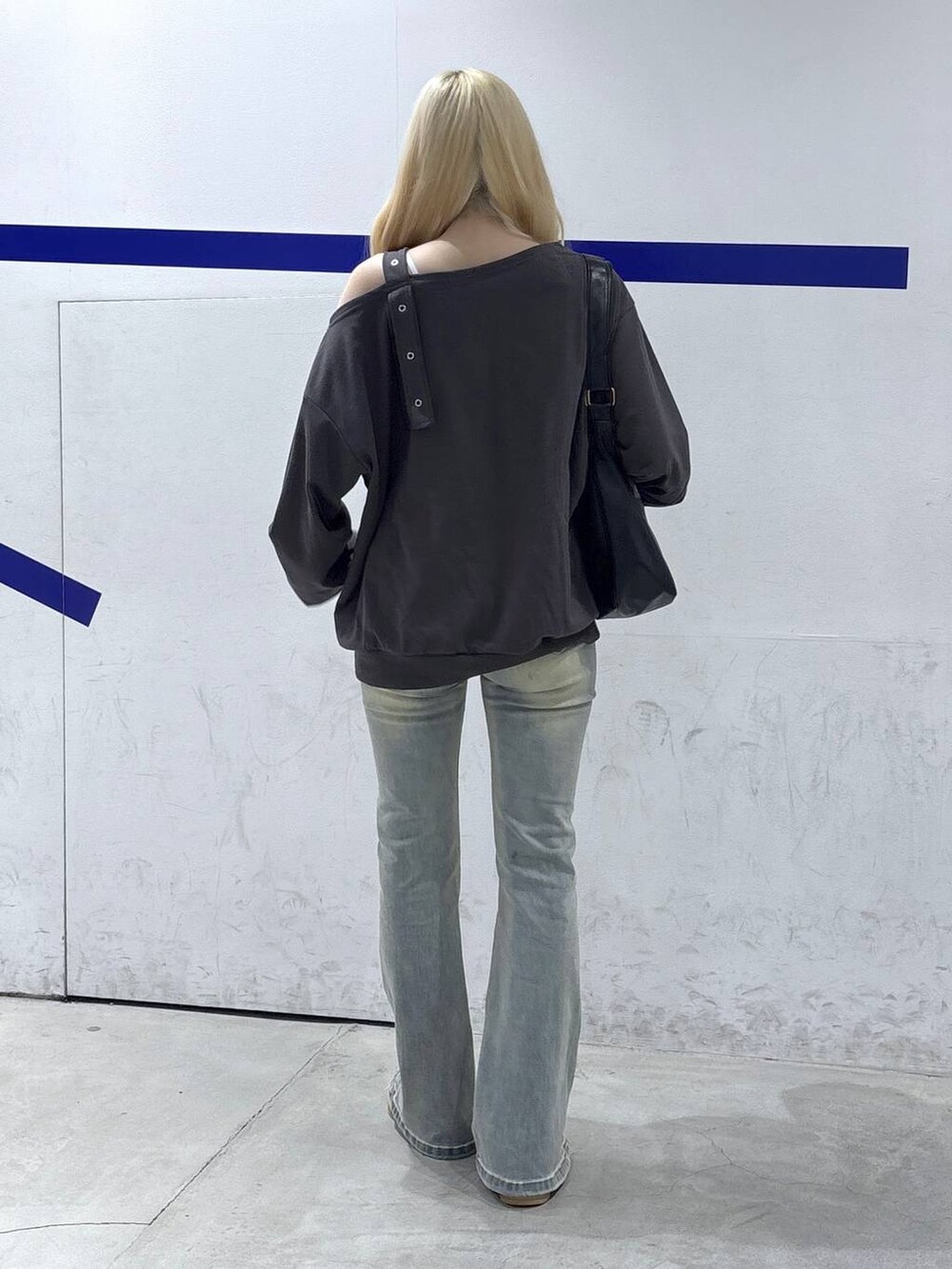 グレー系のスウェット、ブラック系のトートバッグ、ブルー系のデニムパンツを着用したレディースの秋コーディネートの4枚目の写真