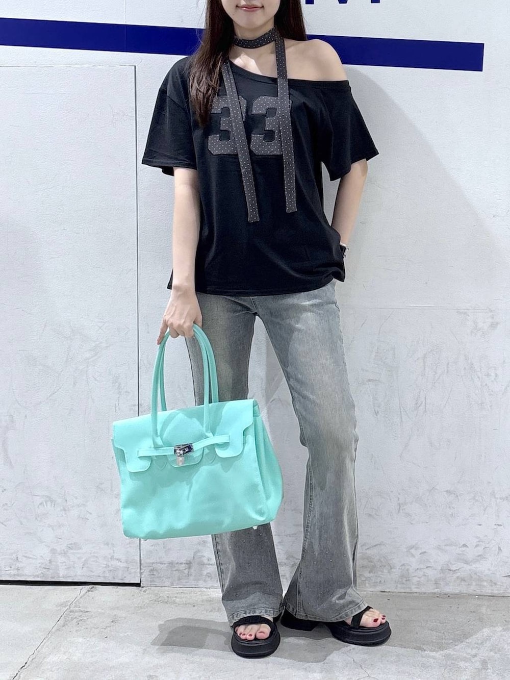 グリーン系のショルダーバッグ、ブラック系のサンダル、ブラック系のTシャツ/カットソーを着用したレディースの夏コーディネートの2枚目の写真
