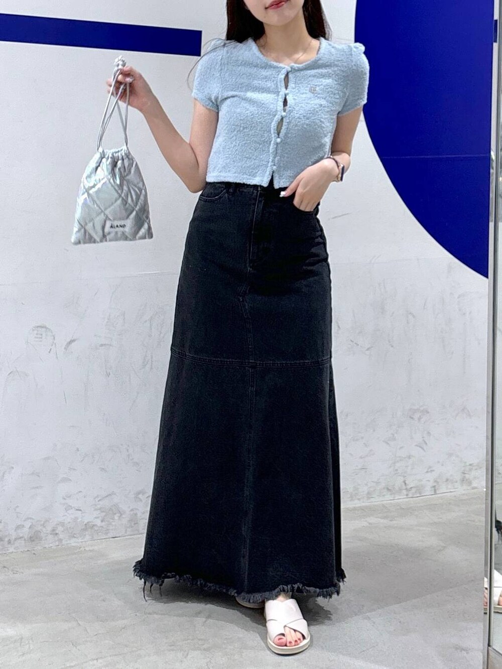 ブラック系のデニムスカート、シルバー系のショルダーバッグ、ブルー系のカーディガン/ボレロを着用したレディースの夏コーディネートの2枚目の写真