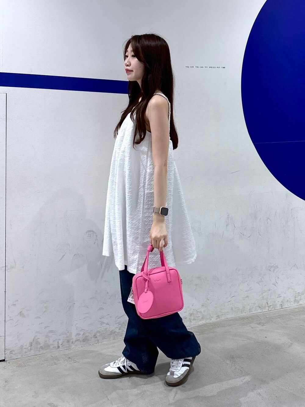 ホワイト系のワンピース、ピンク系のショルダーバッグ、ブルー系のデニムパンツを着用したレディースの夏コーディネートの3枚目の写真