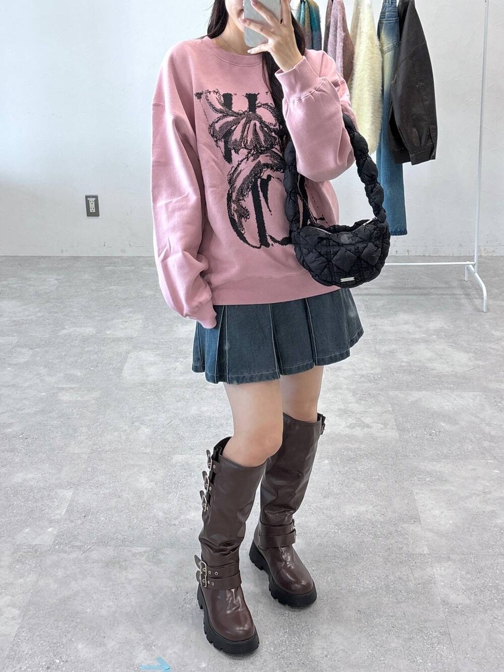 ブラック系のショルダーバッグ、ブルー系のデニムスカート、ブラウン系のブーツを着用したレディースの秋コーディネートの5枚目の写真