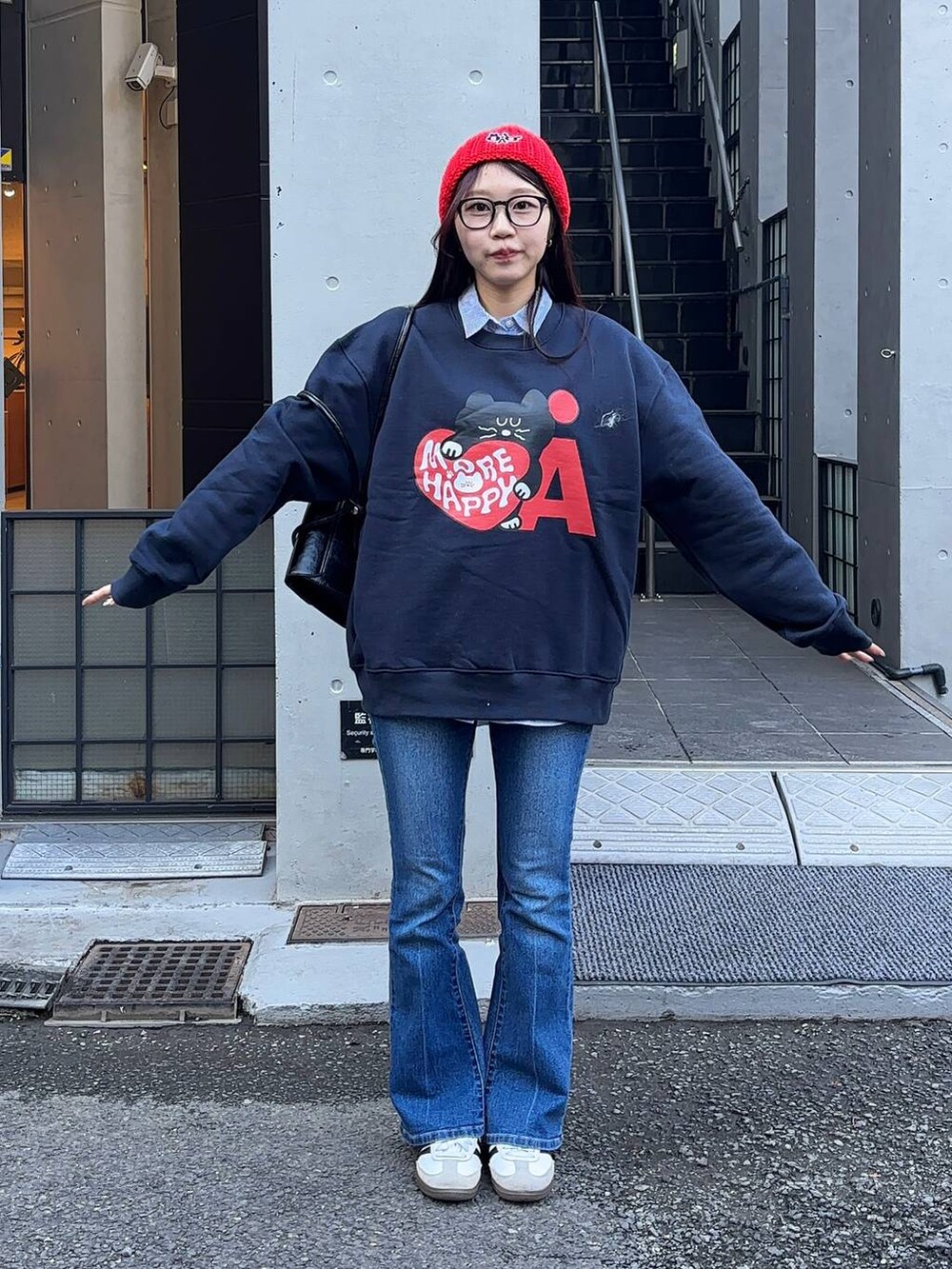 ブルー系のデニムパンツ、ブラック系のショルダーバッグ、ブルー系のスウェットを着用したレディースの冬コーディネートの5枚目の写真