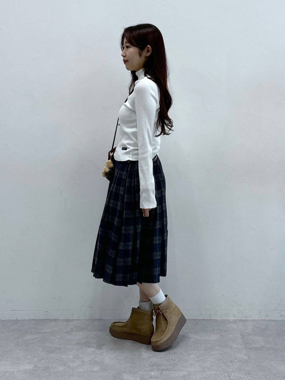 グレー系のスカート、ホワイト系のニット/セーター、ベージュ系のキーホルダーを着用したレディースの秋コーディネートの3枚目の写真