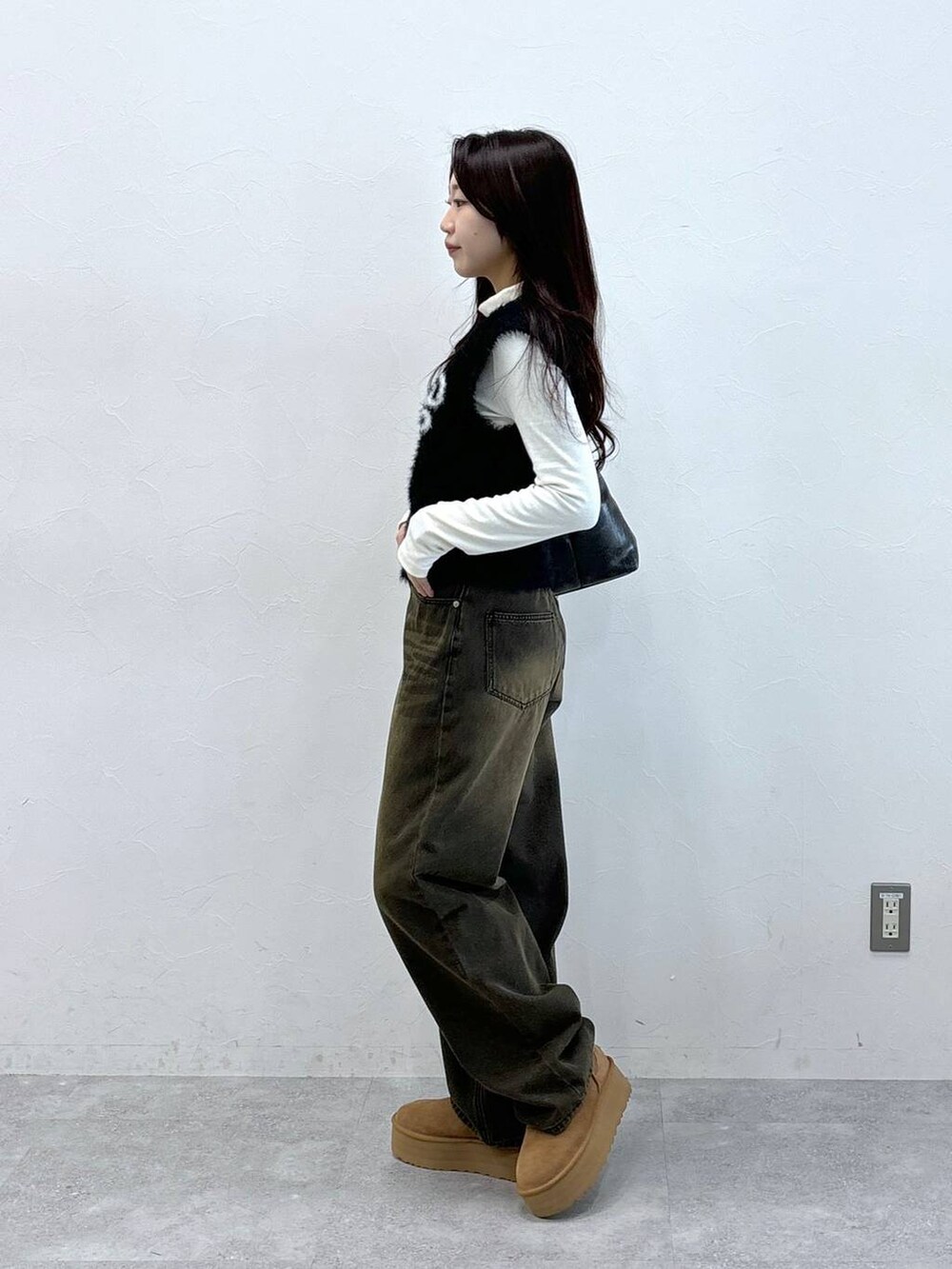 ブラック系のデニムパンツ、ブラック系のベスト、ブラック系のハンドバッグを着用したレディースの秋コーディネートの3枚目の写真