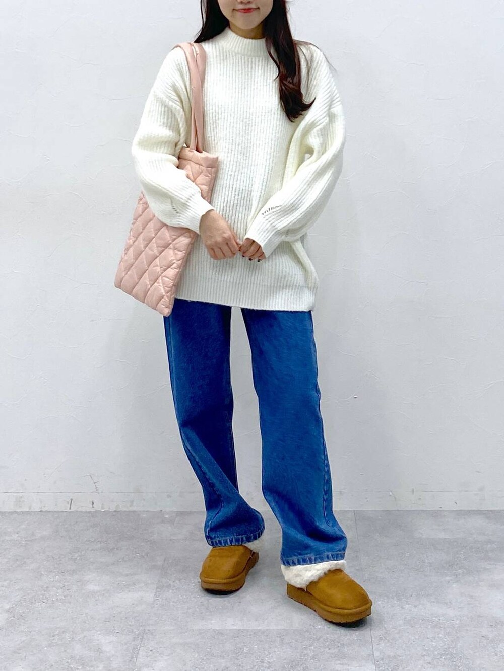 ピンク系のトートバッグ、ブルー系のデニムパンツ、ホワイト系のニット/セーターを着用したレディースの冬コーディネートの3枚目の写真