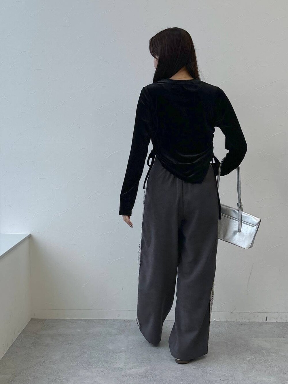 シルバー系のショルダーバッグ、グレー系のスラックス、ブラック系のTシャツ/カットソーを着用したレディースの冬コーディネートの6枚目の写真