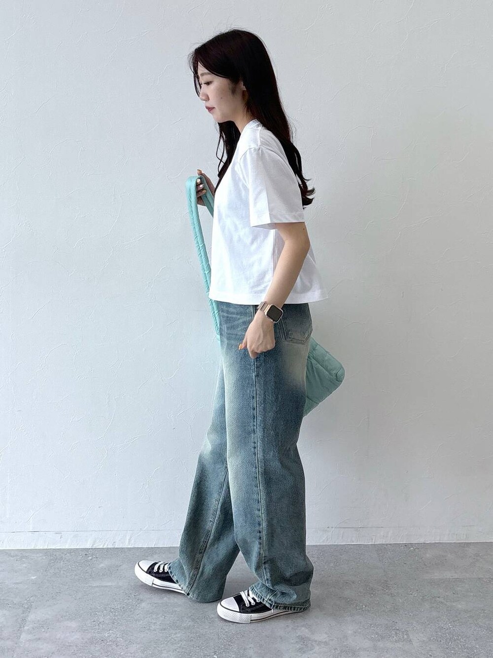 ブルー系のデニムパンツ、グリーン系のショルダーバッグ、ホワイト系のTシャツ/カットソーを着用したレディースの夏コーディネートの5枚目の写真