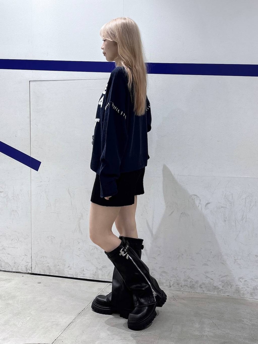 ブラック系のハンドバッグ、ブラック系のブーツ、ブルー系のニット/セーターを着用したレディースの秋コーディネートの3枚目の写真