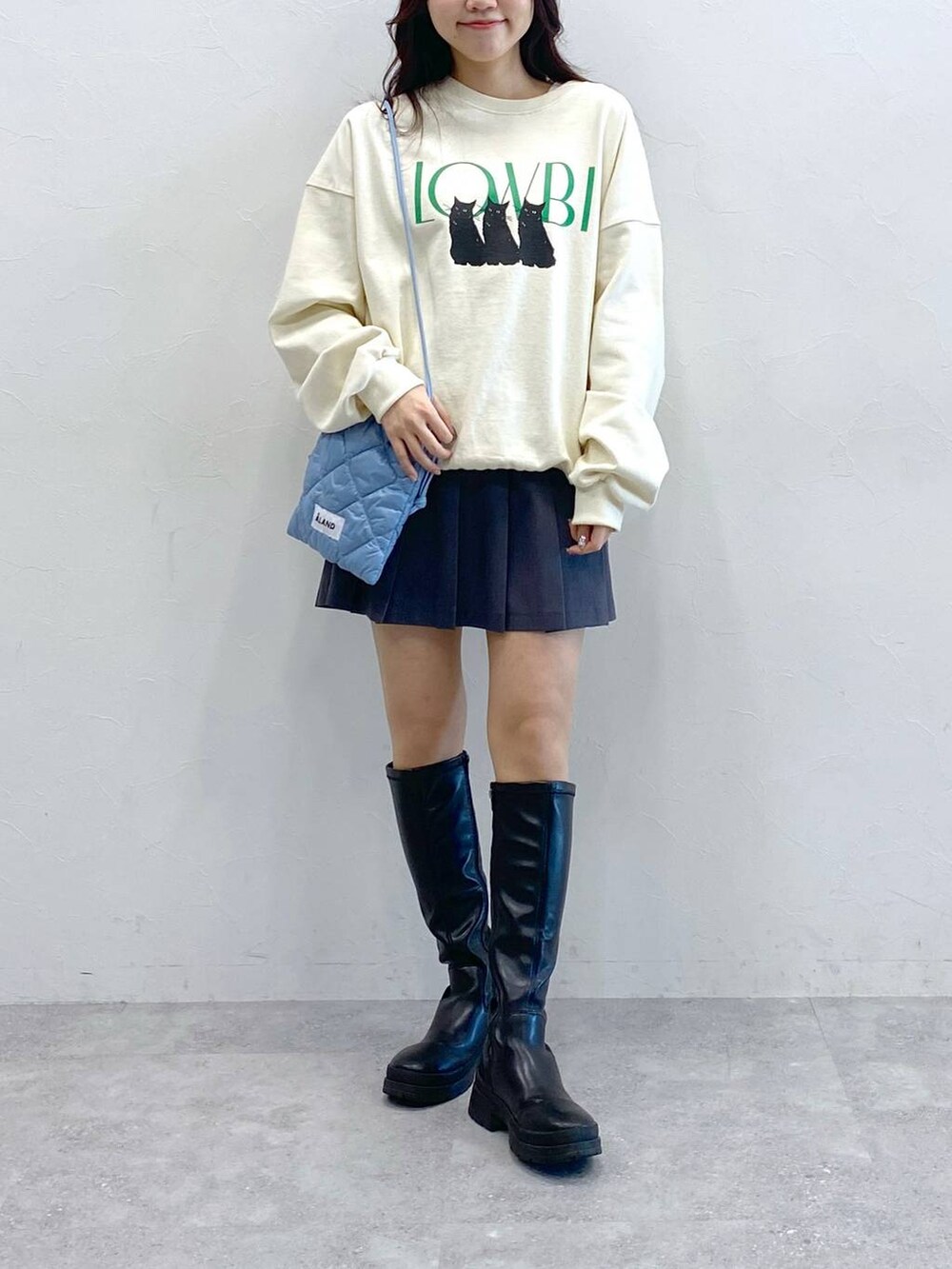 ホワイト系のスウェット、ブルー系のショルダーバッグ、グレー系のスカートを着用したレディースの冬コーディネートの2枚目の写真