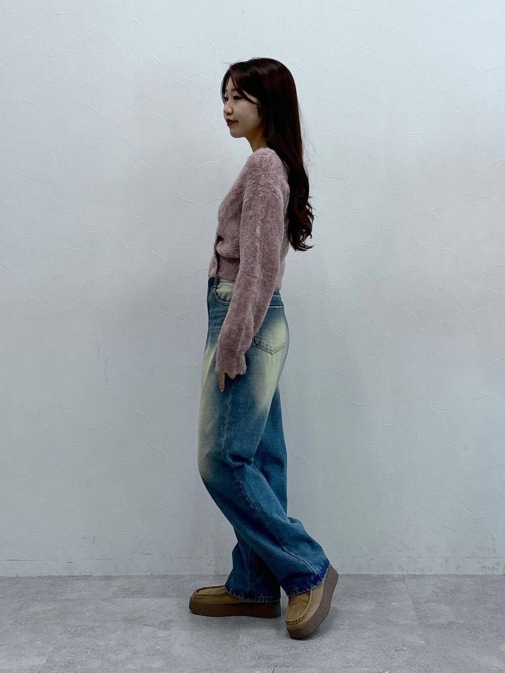 グレー系のショルダーバッグ、オレンジ系のカーディガン/ボレロ、ブルー系のデニムパンツを着用したレディースの秋コーディネートの3枚目の写真