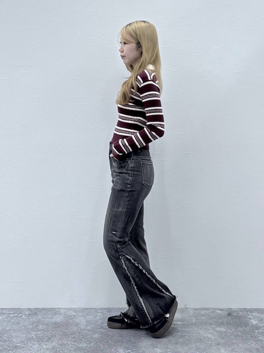 レッド系のニット/セーター、ブラック系のデニムパンツを着用したレディースの秋コーディネートの3枚目の写真