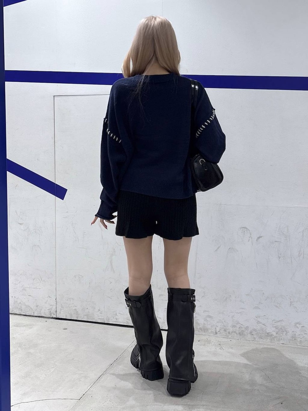 ブラック系のハンドバッグ、ブラック系のブーツ、ブルー系のニット/セーターを着用したレディースの秋コーディネートの4枚目の写真