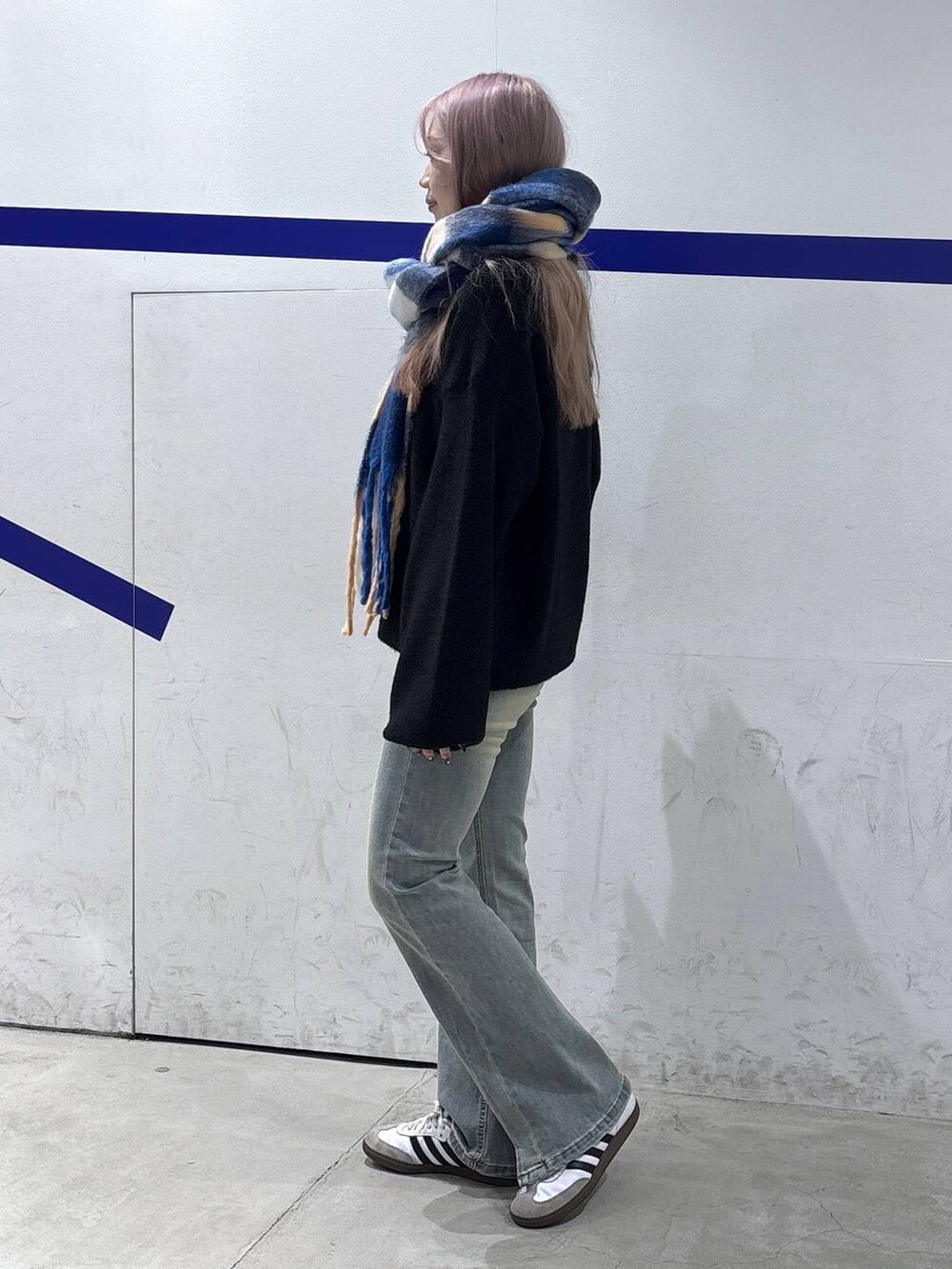 ブルー系のデニムパンツ、ブラック系のニット/セーター、ブラック系のショルダーバッグを着用したレディースの秋コーディネートの4枚目の写真