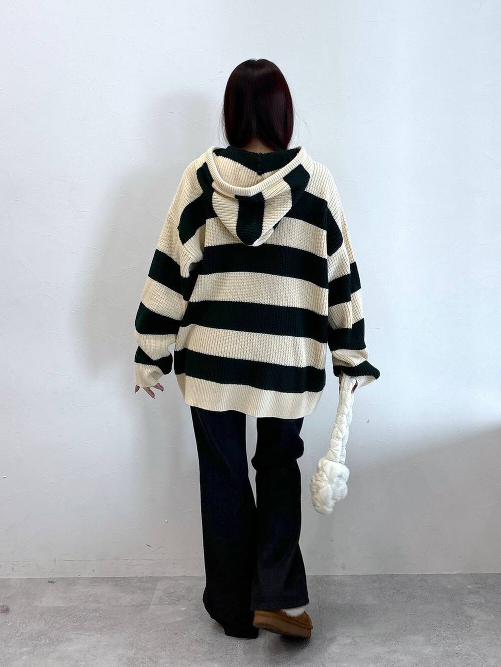 ホワイト系のショルダーバッグ、ブラック系のデニムパンツ、グリーン系のニット/セーターを着用したレディースの冬コーディネートの4枚目の写真