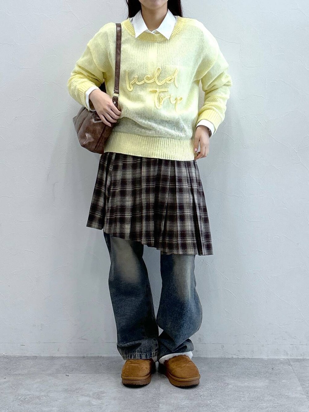 ブルー系のデニムパンツ、ブラウン系のスカート、ブラウン系のハンドバッグを着用したレディースの冬コーディネートの2枚目の写真