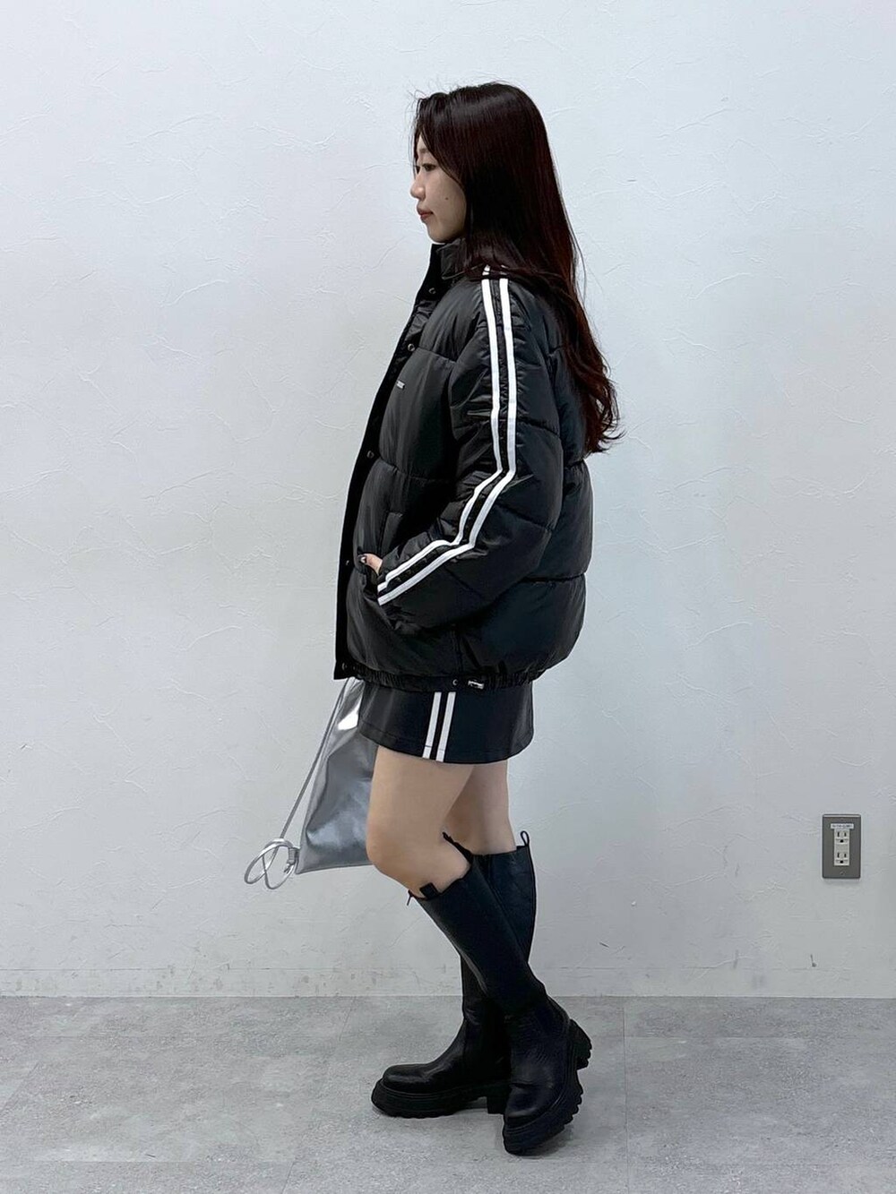 ブラック系のスカート、ブラック系のダウンジャケット/コート、ブラック系のブーツを着用したレディースの秋コーディネートの4枚目の写真