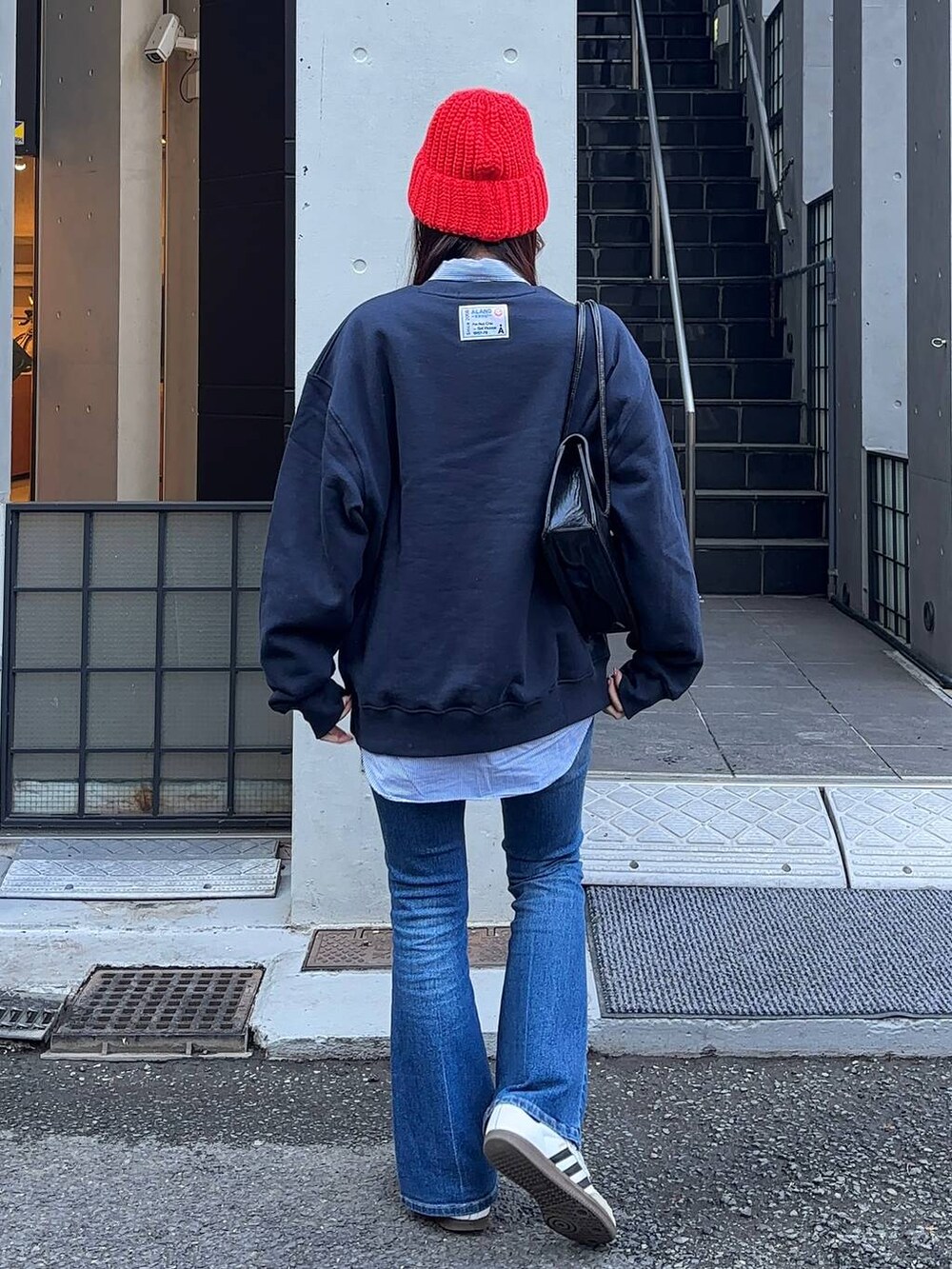 ブルー系のデニムパンツ、ブラック系のショルダーバッグ、ブルー系のスウェットを着用したレディースの冬コーディネートの4枚目の写真