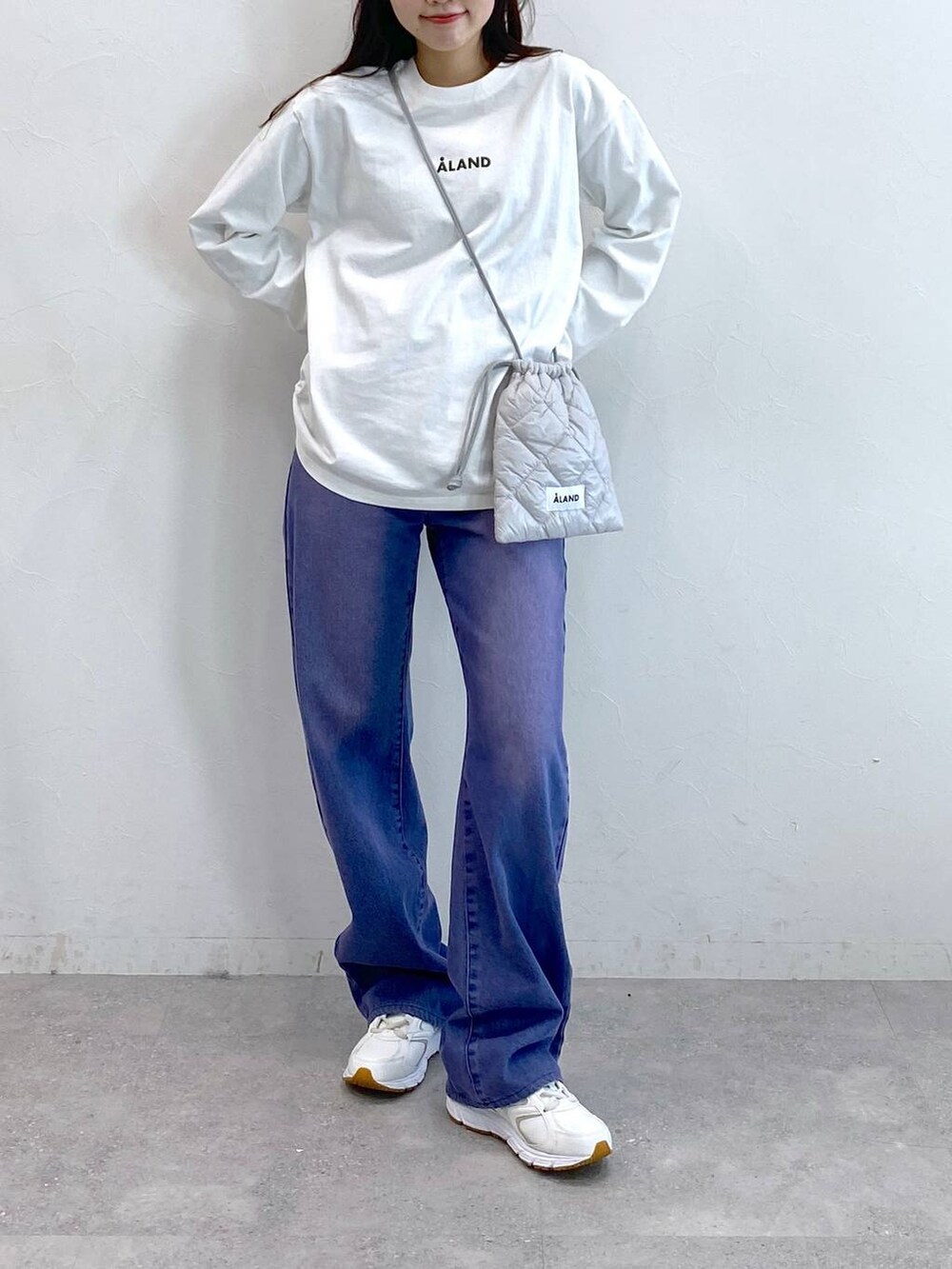 パープル系のデニムパンツ、グレー系のショルダーバッグ、ホワイト系のTシャツ/カットソーを着用したレディースの冬コーディネートの2枚目の写真